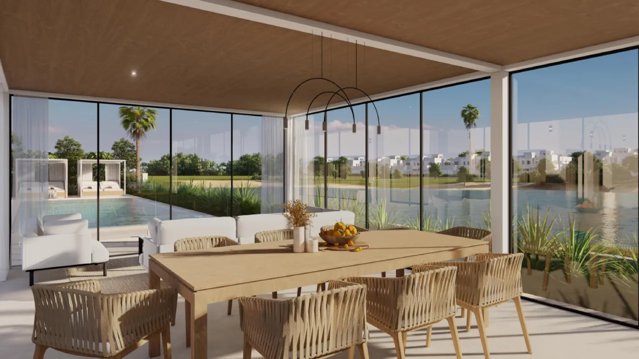 Glass sunroom living and dining area overlooking the pool with woven chairs, white sofa and warm wood ceiling