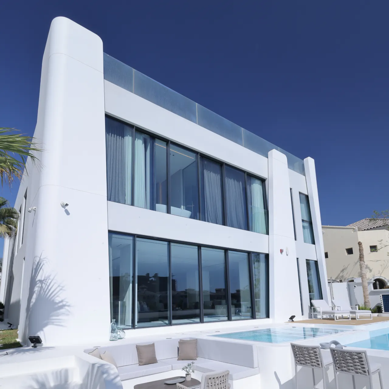 Modern exterior elevation design of a fully renovated house in Palm Jumeirah Dubai with stylish white facade and black framed large windows