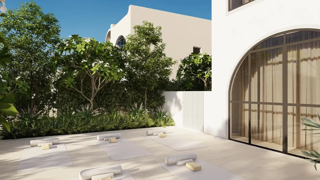 Outdoor yoga space in a private backyard with pale mats, arched glass doors, white walls and lush garden planting
