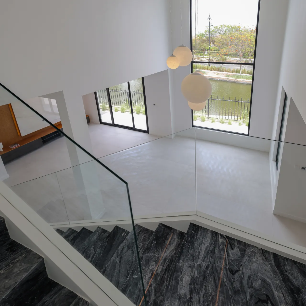 Villa staircase area with renewed flooring, updated finishes, glass railing, and a brighter interior appearance