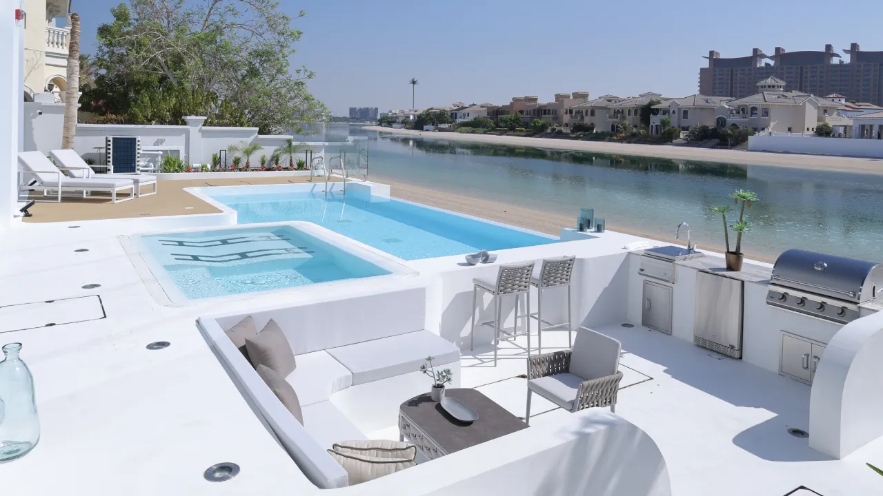 Beachfront Palm Jumeirah villa renovation with infinity pool, terrace, outdoor kitchen, integrated Jacuzzi, seating area, and direct beach access.