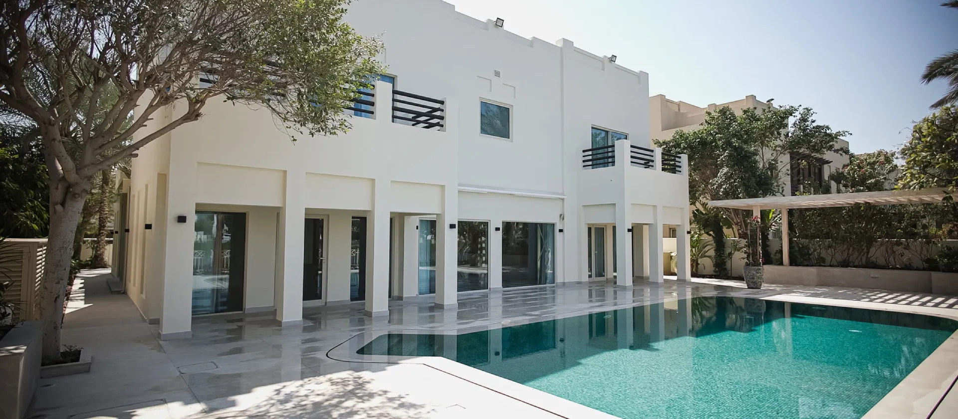 Meadows Dubai home renovation with refreshed white villa facade, large swimming pool, terrace, and landscaped backyard.