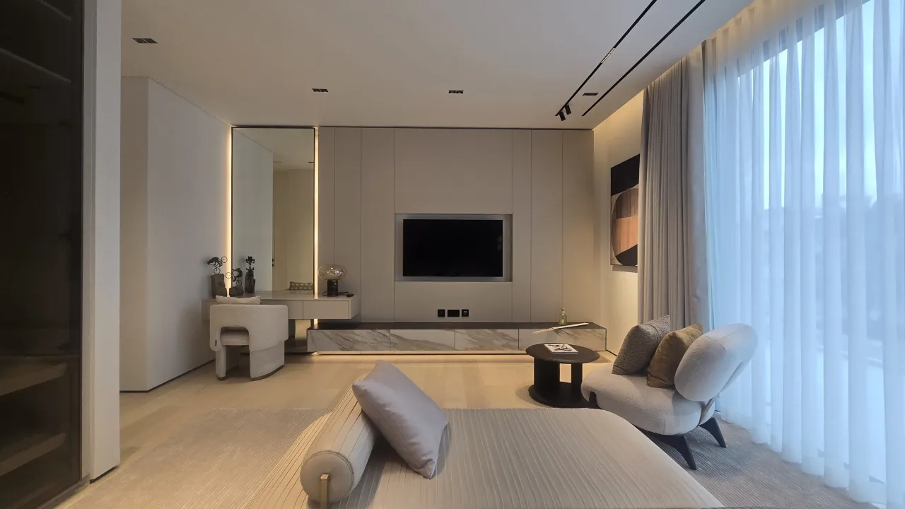 Modern bedroom renovation with vanity corner, low TV wall, marble console, lounge seating, sheer curtains and soft neutral finishes