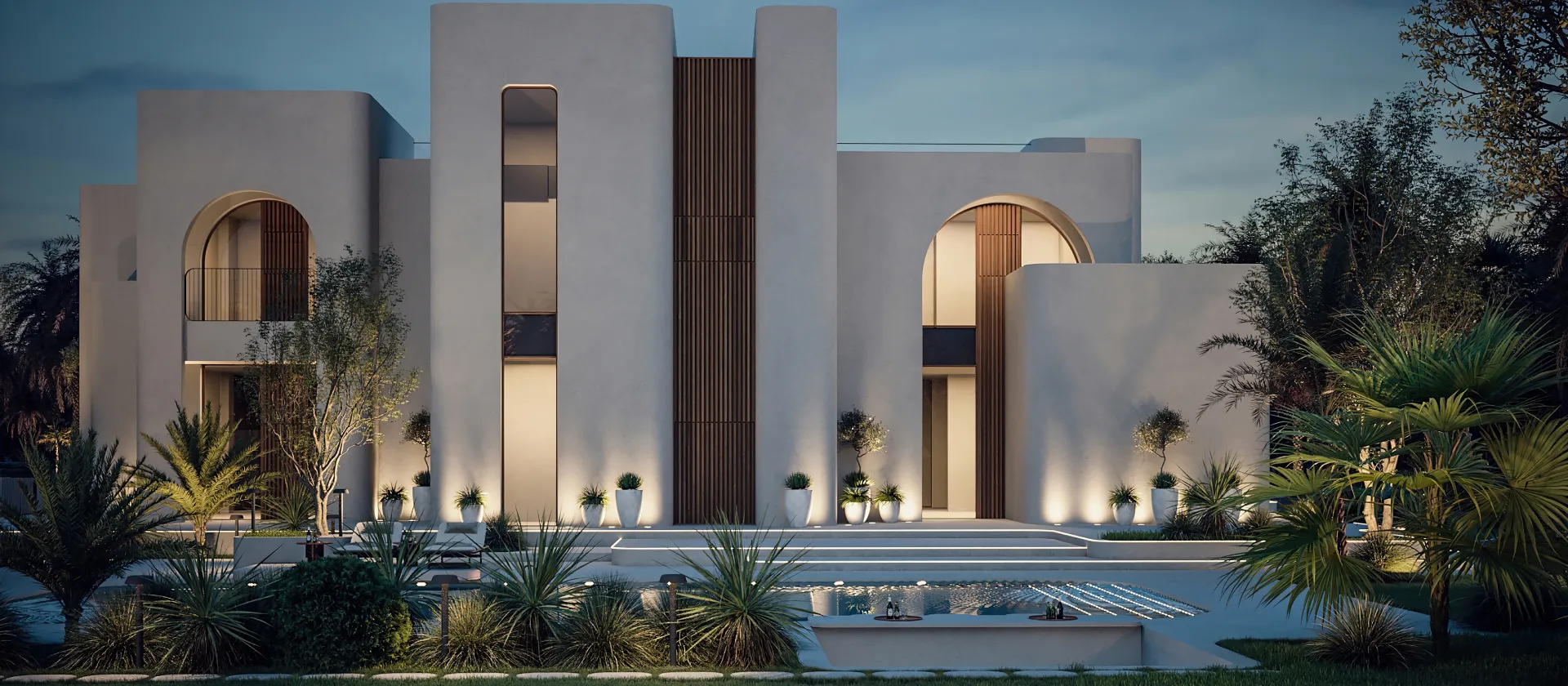 Contemporary villa exterior with curved architecture, layered tropical planting, landscape lighting, and a large decorative water feature at dusk.