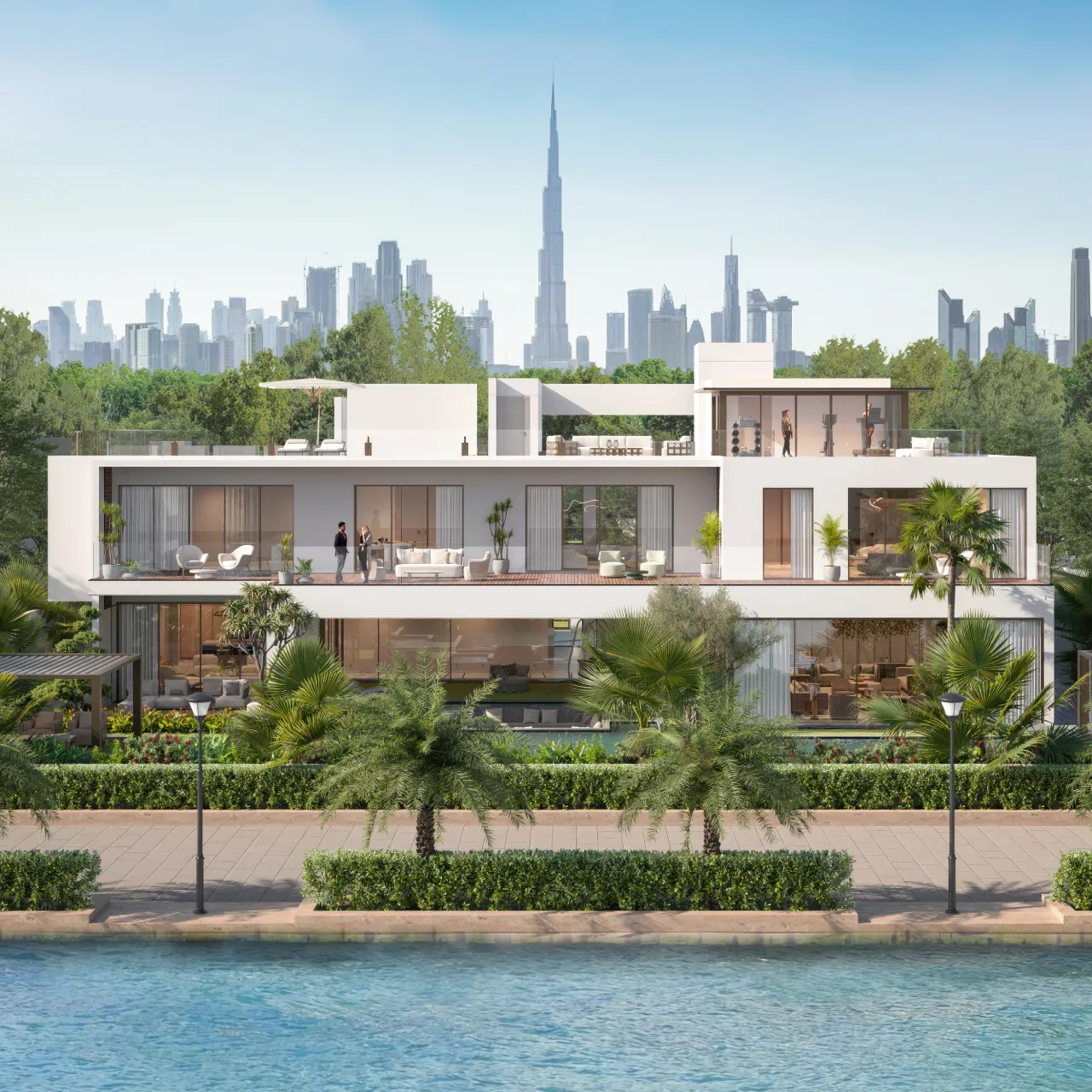 A contemporary white waterfront house with layered terraces, large glass windows, rooftop seating, lush landscaping, and a view of the Burj Khalifa and Dubai skyline in the background.