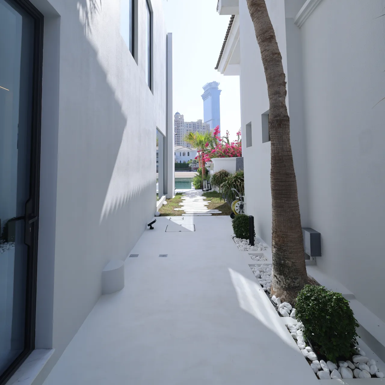 A modern Palm Jumeirah villa with swimming pool, stone pool deck, outdoor hard surface landscaping, glass facade, garden edges, and waterfront outdoor area.