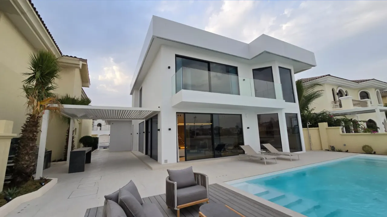 Palm Jumeirah villa rear exterior after renovation with large glass doors, flat roof, glass balcony and pool terrace