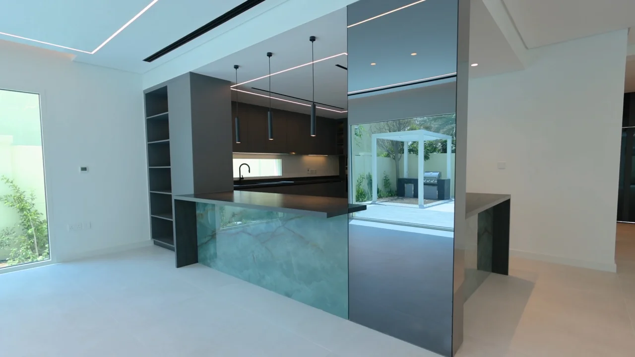 Dark kitchen island with stone panels, mirrored column and garden view in a renovated Jumeirah Park house