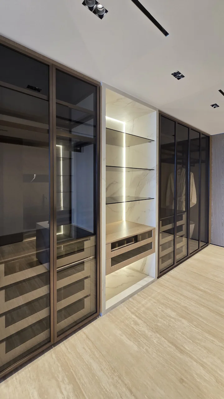 Dressing room with bathroom featuring smoked-glass wardrobes and illuminated display shelving