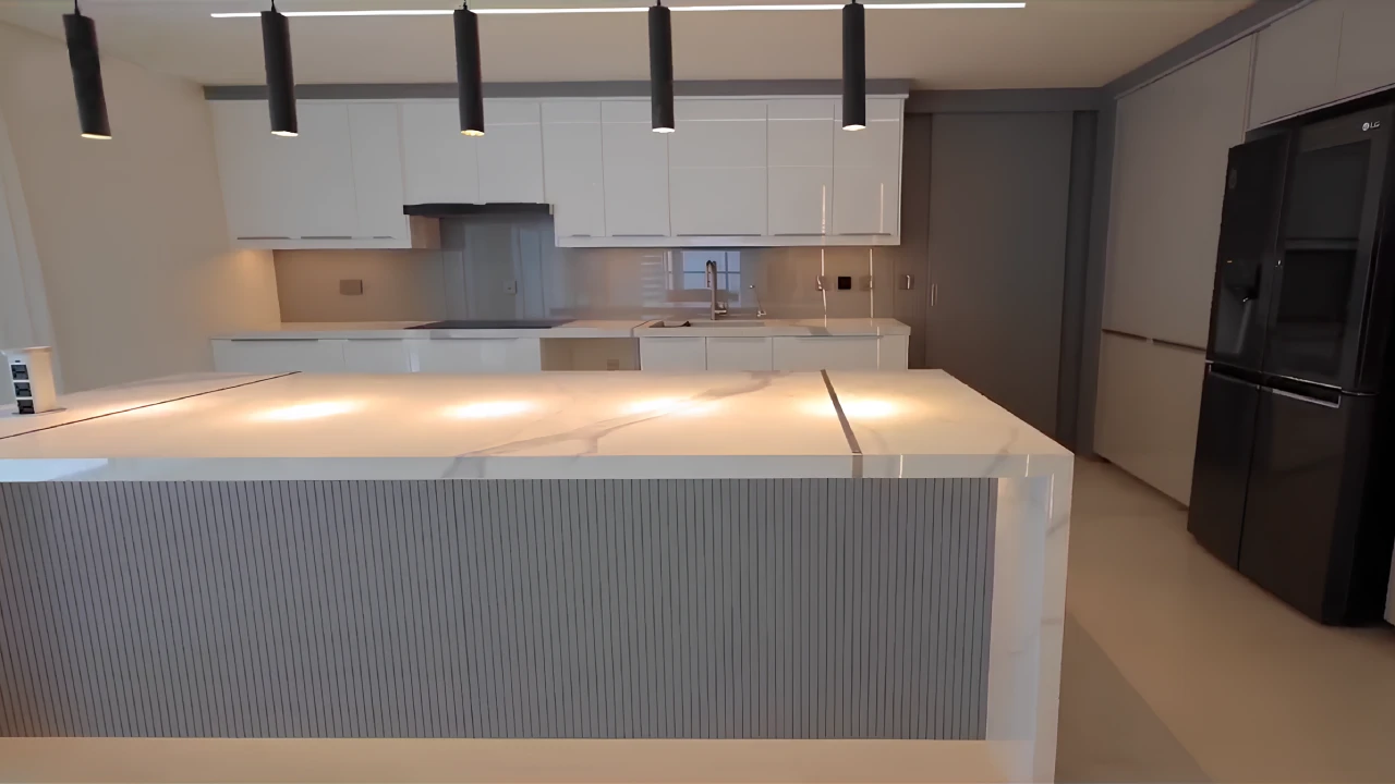 White kitchen with a large marble-look waterfall island and black pendant lights in Dubai Marina