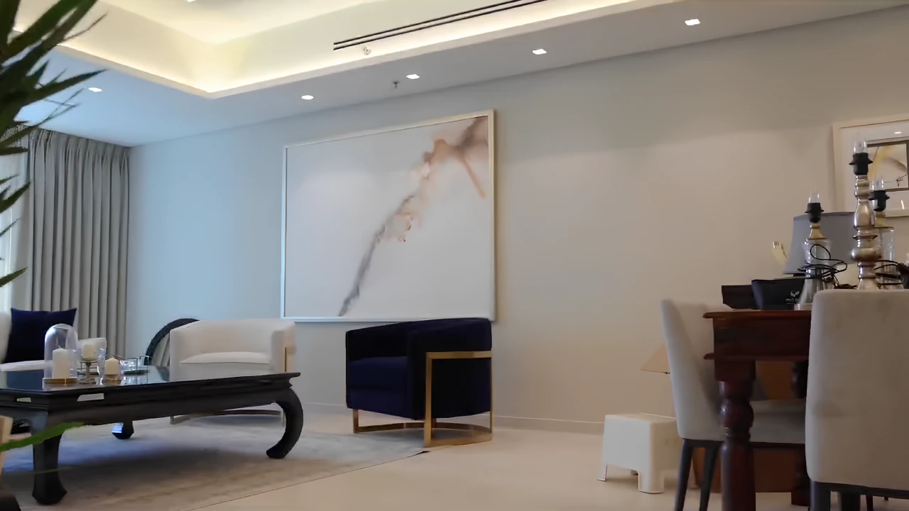 Ivory seating, navy accent chair, dark wood furniture and large artwork in the renovated Emirates Crown apartment living room