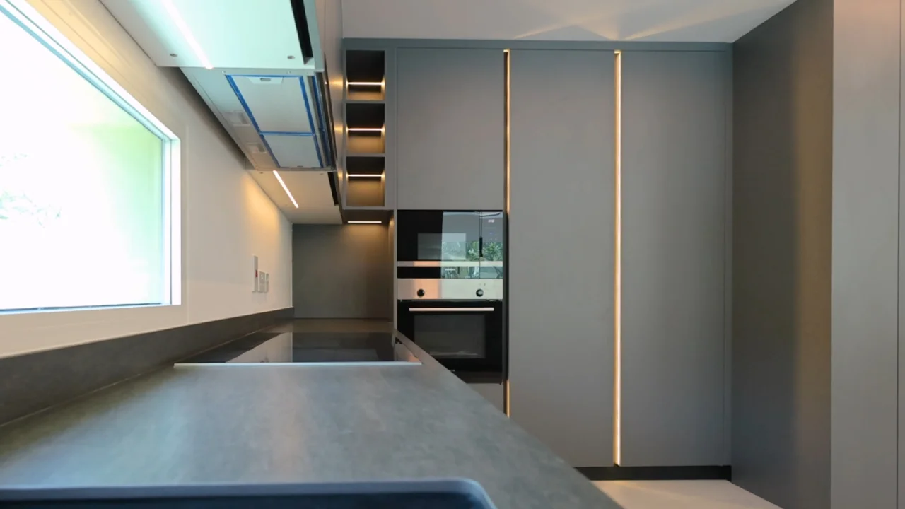 Full-height grey kitchen cabinets with integrated ovens and vertical lighting in a Jumeirah Park villa