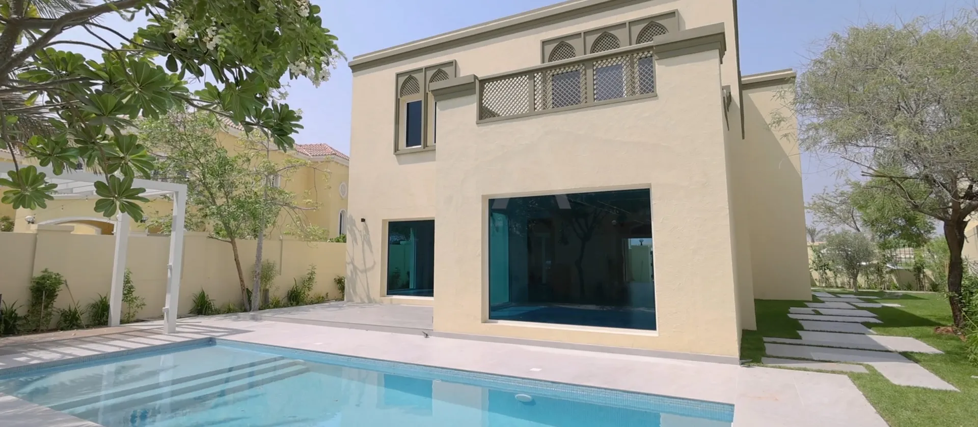 Rear exterior of a renovated Regional Type 4V villa with large garden windows and swimming pool in Jumeirah Park