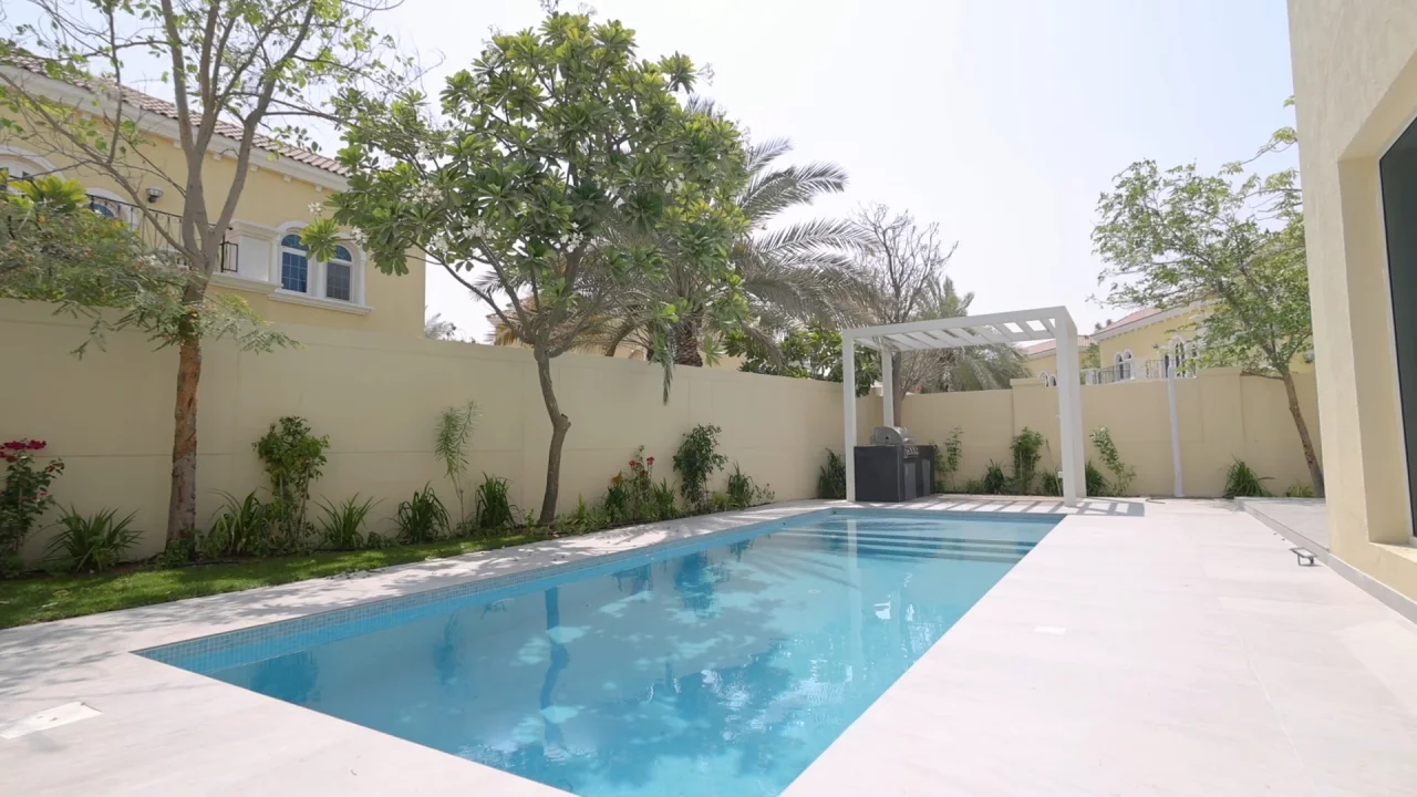 Updated rectangular swimming pool with pale terrace, planted garden and white barbecue pergola in Jumeirah Park