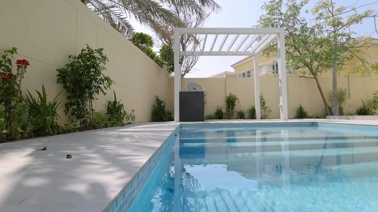 Remodeled swimming pool with wide entry steps, pale terrace and white barbecue pergola in a garden