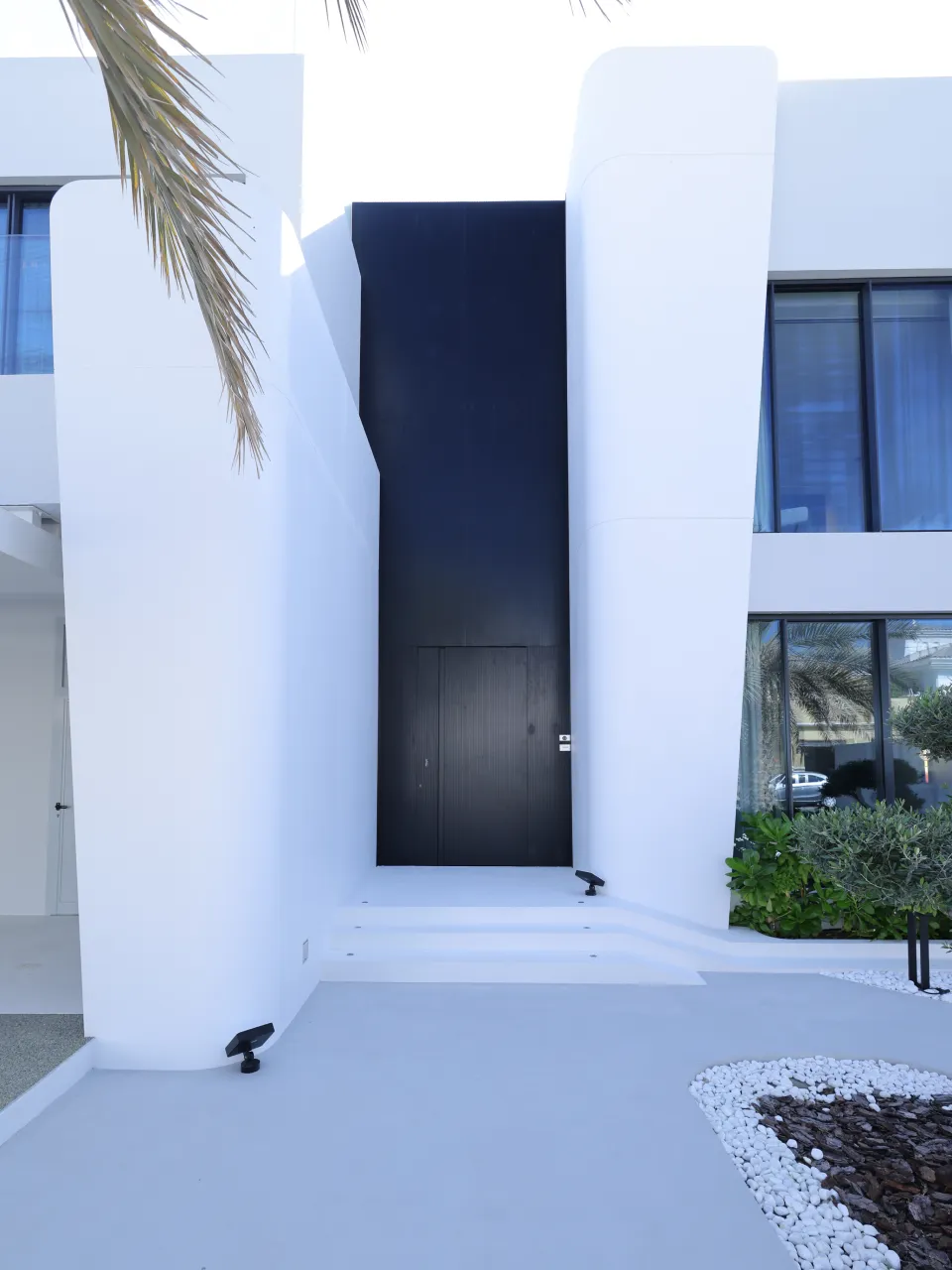 Oversized black entrance door and tall white facade forms after Palm Jumeirah villa remodeling
