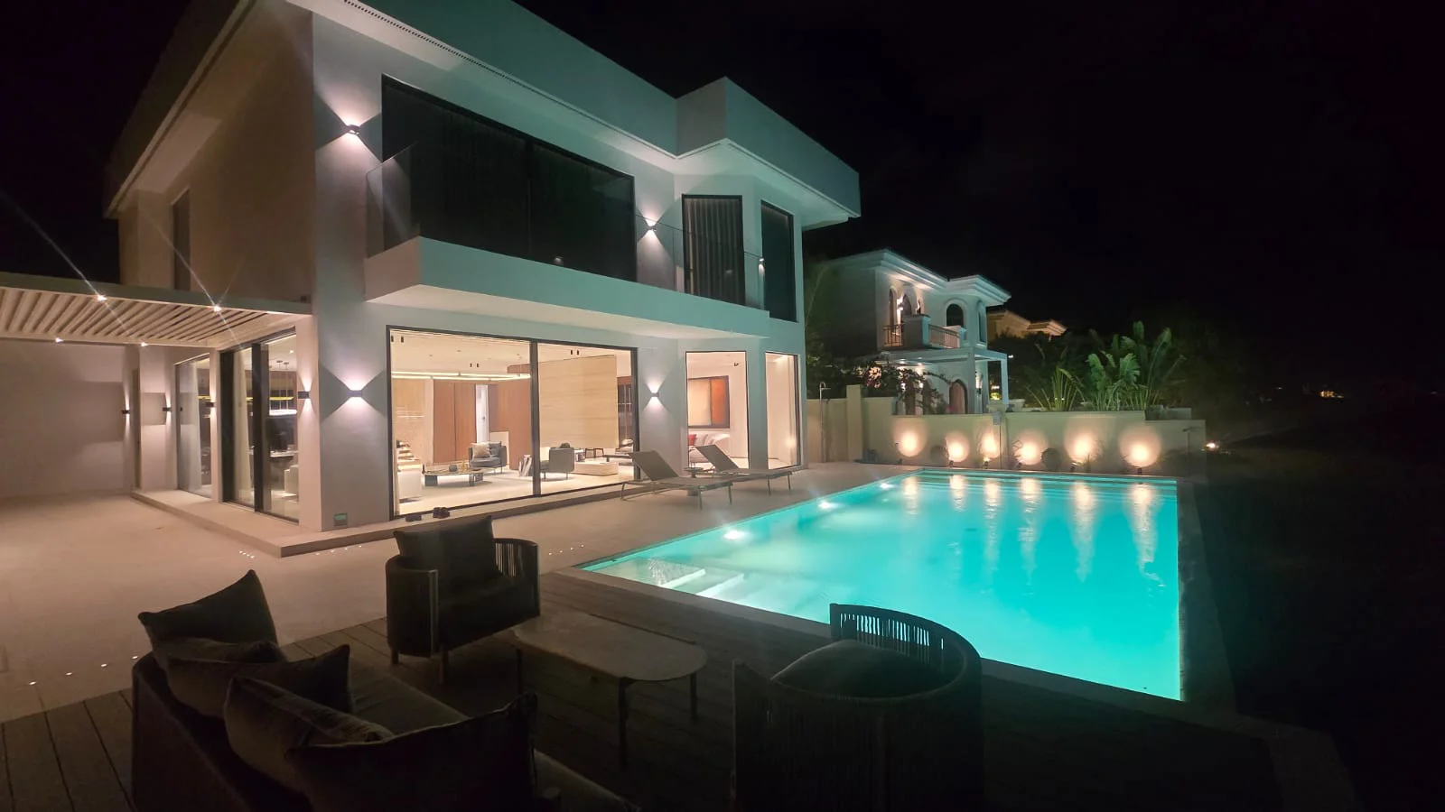 Remodeled Palm Jumeirah villa pool at night with underwater lights, wall uplights, illuminated glazing and covered terrace