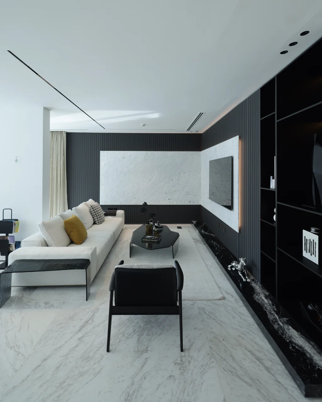 Palm Jumeirah family living room with dark fluted TV wall, white marble feature panel, cream sofa, black coffee table, light rug, and display shelving