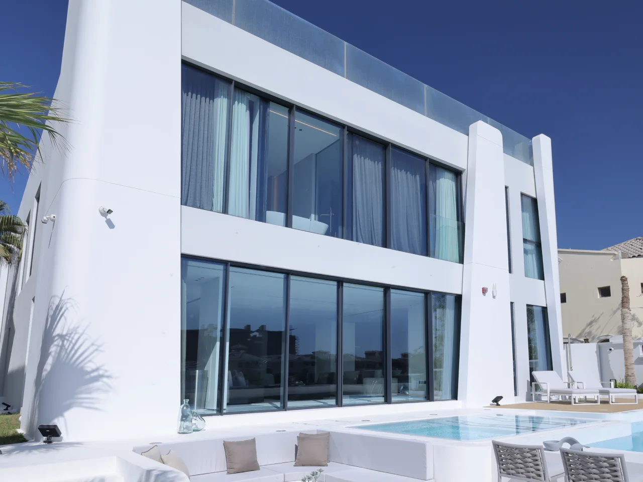 Contemporary rear elevation with large glazing, pool terrace and sunken seating after remodeling