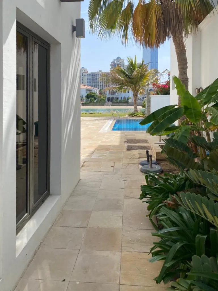 Original narrow side path with beige paving and dense tropical planting