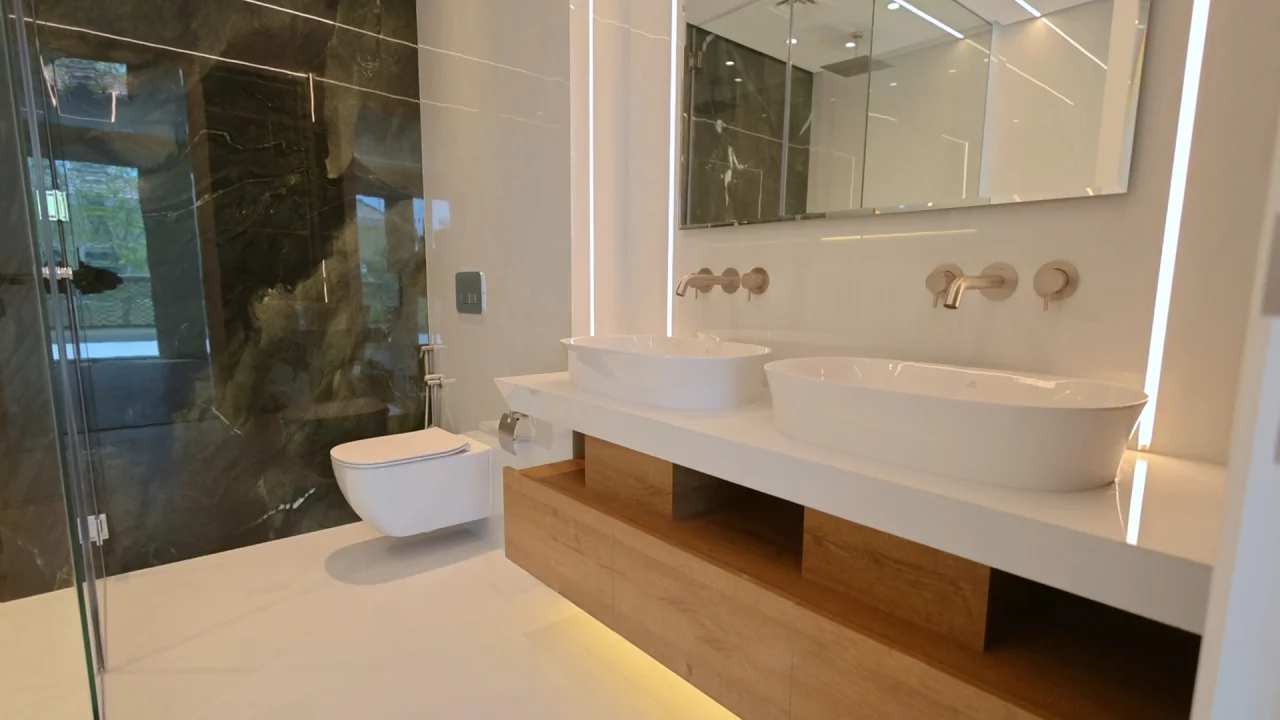 bathroom with double vessel basins, floating wood vanity and dark stone shower wall in a Jumeirah Park house 