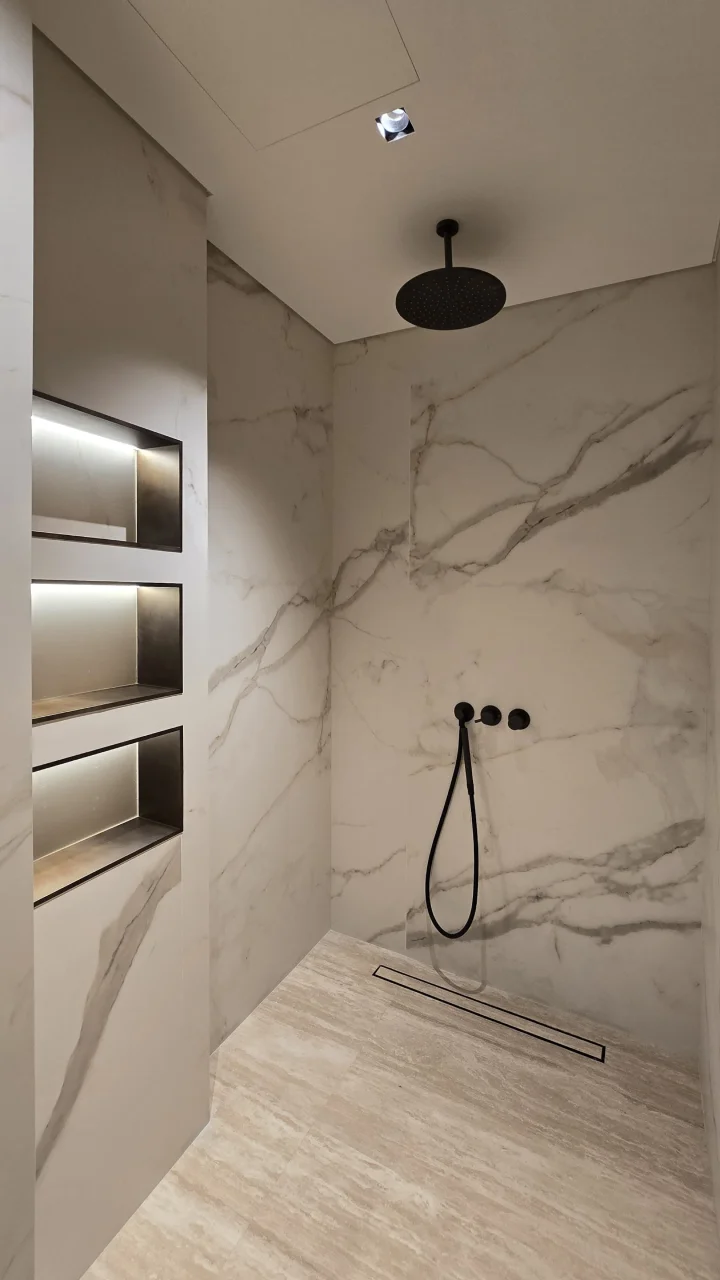 Walk-in shower with marble-effect slabs, black fittings and illuminated niches