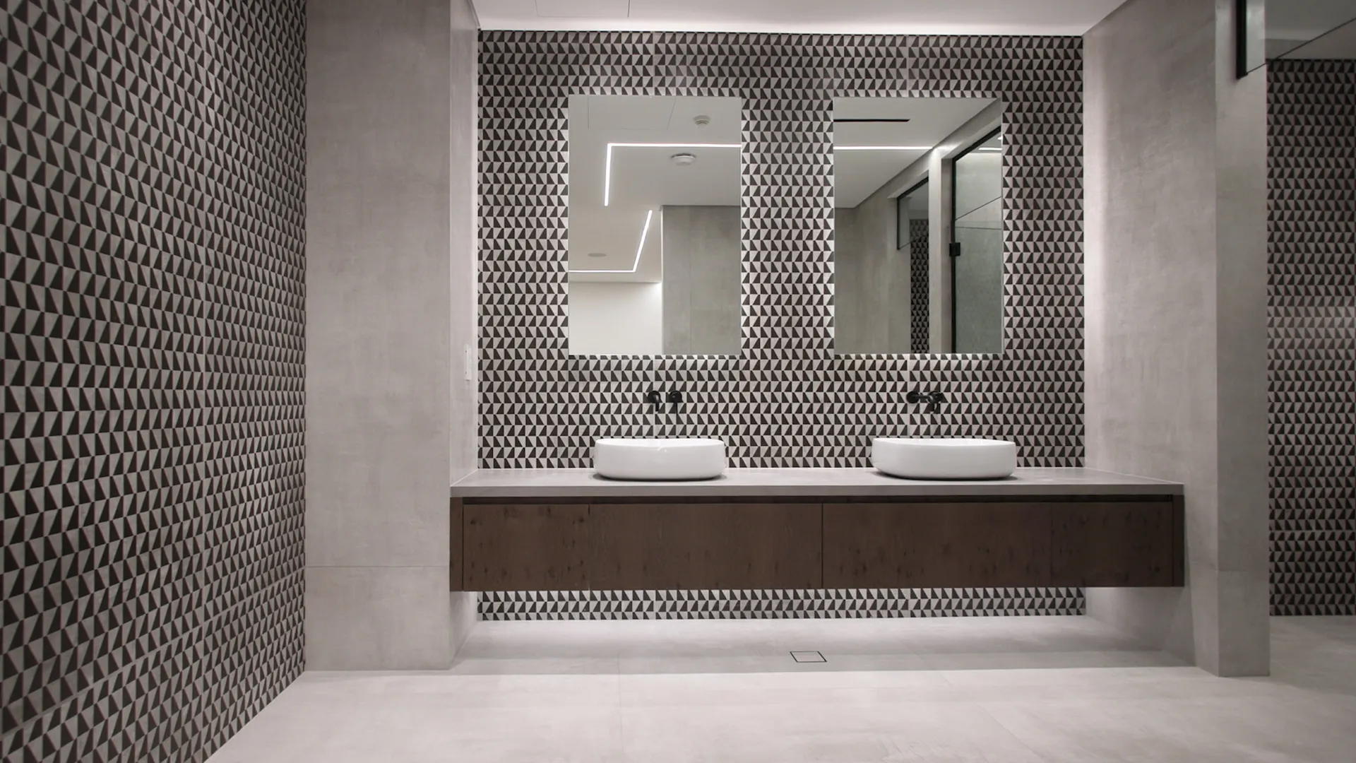 Ensuite bathroom with two vessel basins, floating timber vanity and black-and-white geometric mosaic walls