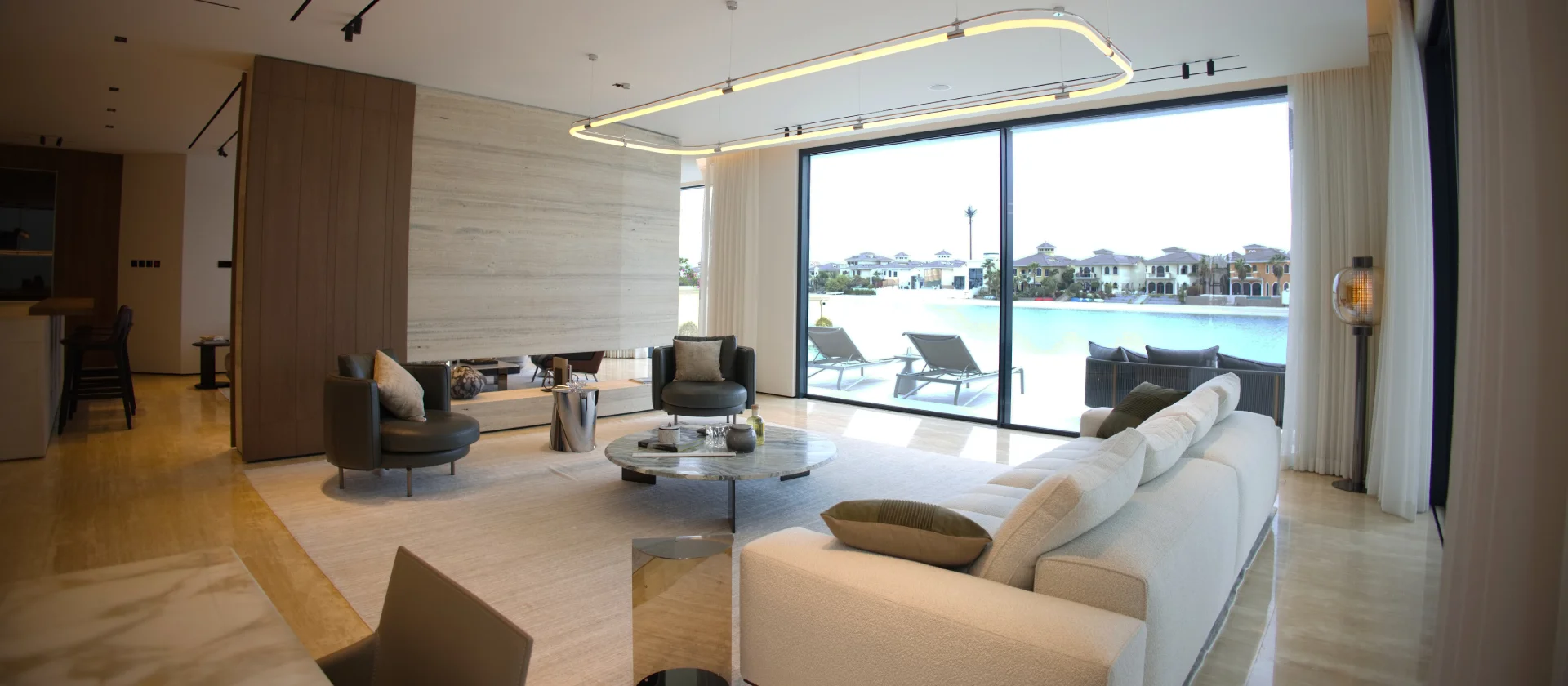 Renovated ground-floor living room in a luxury Palm Jumeirah villa featuring modern furniture, marble finishes, floor-to-ceiling windows, and waterfront views.