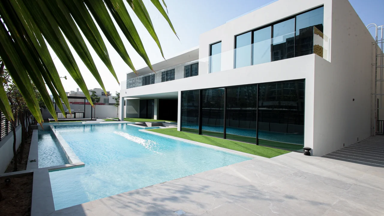 Daytime view of the Casa Azul rear elevation with black-framed glazing, first-floor balconies and the long swimming pool
