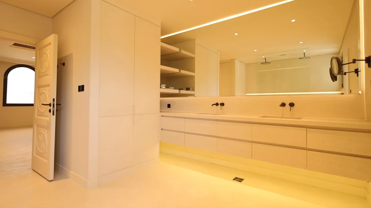 Garden Home bathroom renovation on Palm Jumeirah with long floating vanity, integrated storage, open shelving, black wall-mounted taps and illuminated mirror
