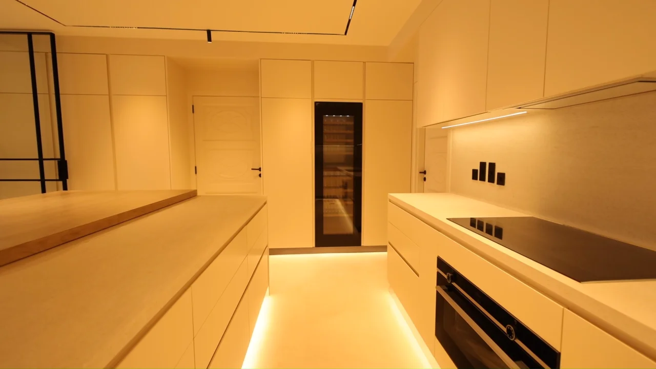 Garden Home kitchen renovation on Palm Jumeirah with large central island, induction hob, integrated oven, tall appliance cabinetry and under-cabinet lighting