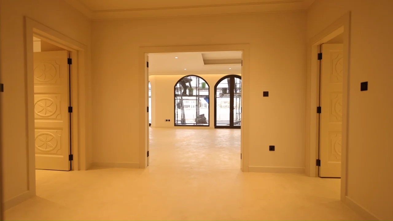 Interior hall of the renovated Palm Jumeirah Garden Home opening into the living room with original arched windows and decorative paneled doors