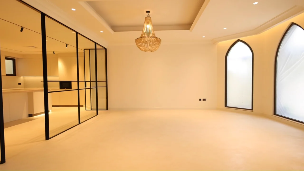 Renovated dining room in a Palm Jumeirah villa with pointed arched windows, pendant light and black steel-framed glass kitchen partition
