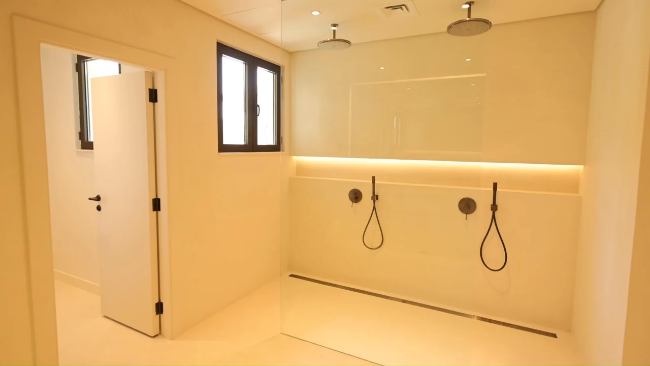 Large walk-in shower in the renovated Palm Jumeirah villa with two ceiling rain showers, twin handheld fittings, frameless glass and linear drain