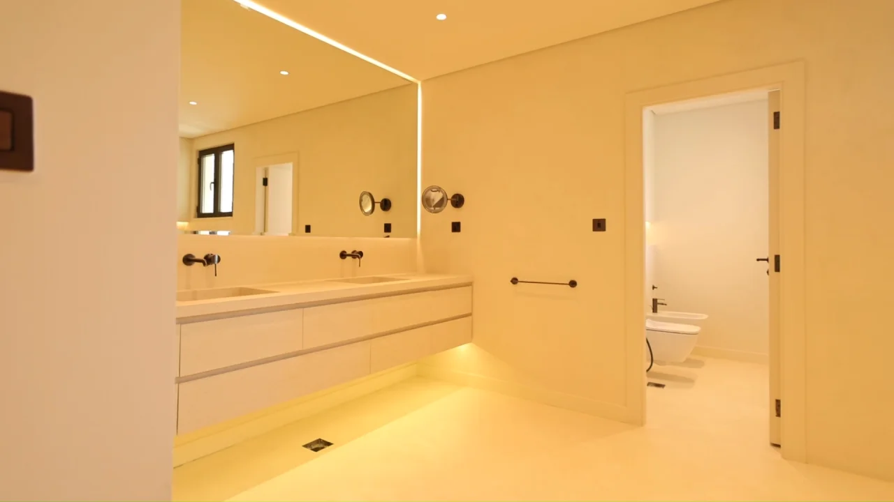 Renovated Palm Jumeirah villa bathroom with long floating double vanity, integrated basins, wall-mounted black taps and illuminated full-width mirror