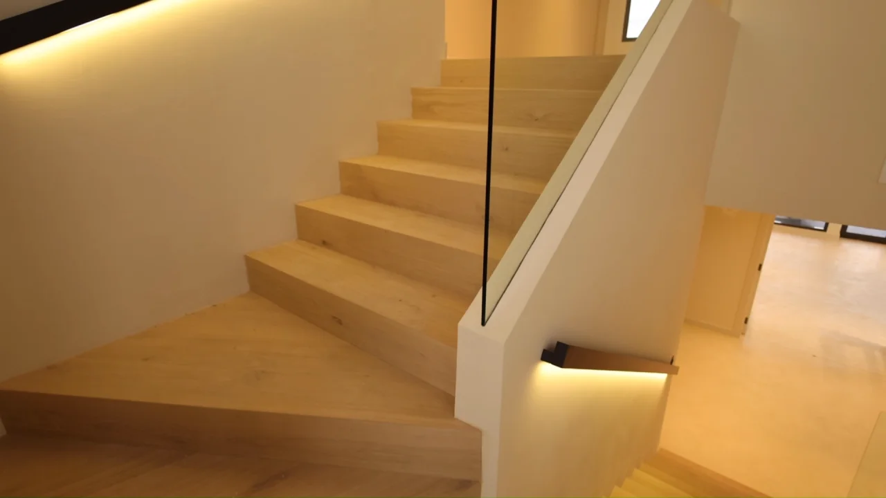 Palm Jumeirah villa staircase with sandy finish, clear glass balustrade, dark handrail and concealed linear LED lighting