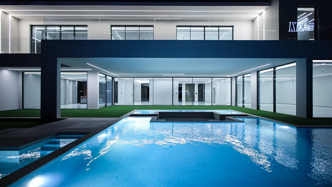 Front view of the illuminated swimming pool with a fixed sunken seating lounge surrounded by water