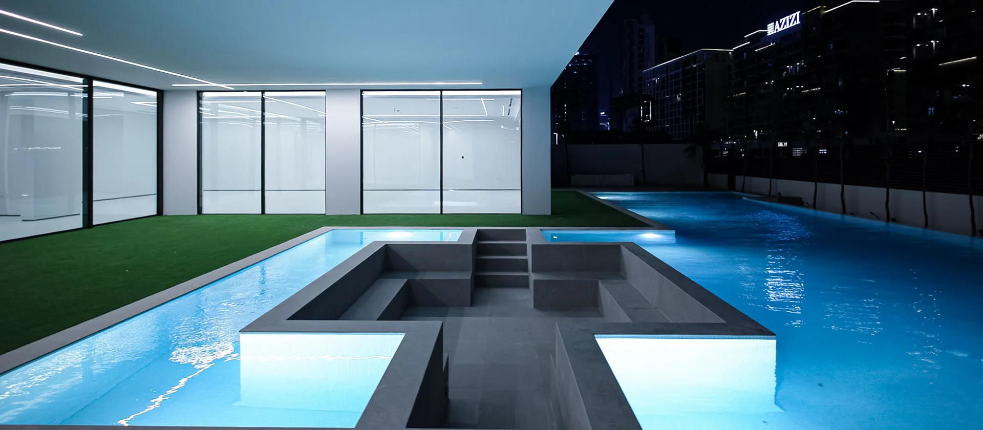 Luxury private Dubai villa with a large swimming pool featuring a fixed sunken seating lounge surrounded by water.