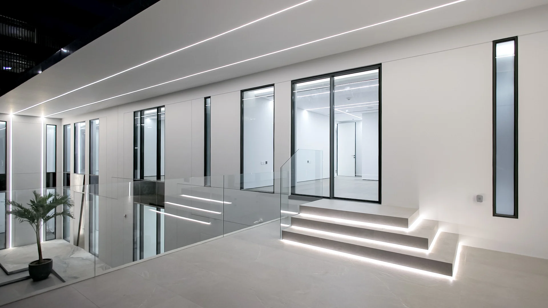 Raised terrace with glass balustrades, illuminated steps, full-height windows and integrated linear lighting