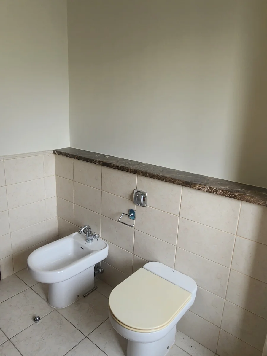 Meadows bathroom before renovation with floor-standing toilet, separate bidet and beige wall tiles