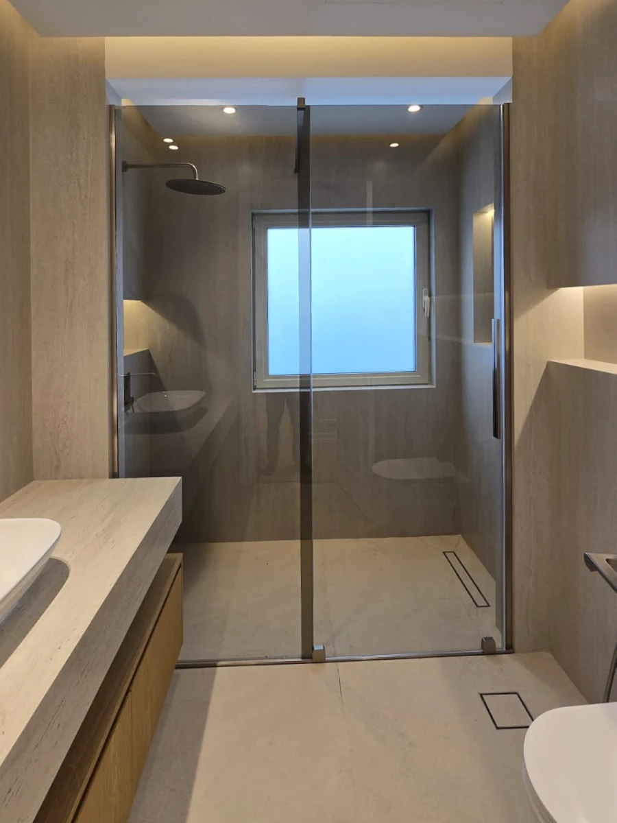 Renovated Meadows bathroom with glass walk-in shower, light stone surfaces and rain shower