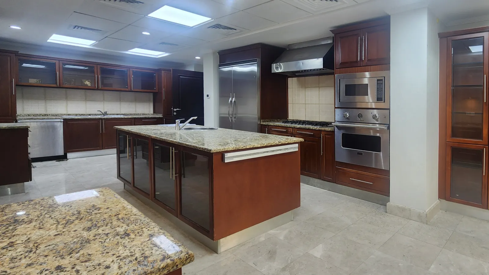 Original Meadows kitchen appliance wall with freestanding refrigerator, stainless steel oven stack and dark cherry cabinetry