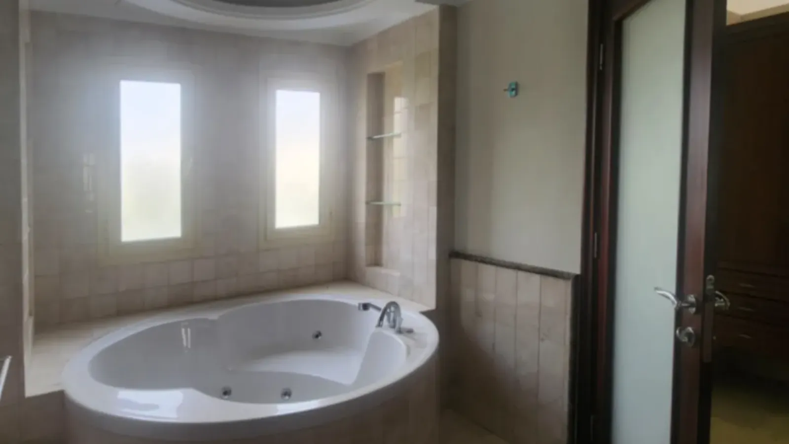 The Meadows master bathroom before renovation with curved spa bath and two narrow windows