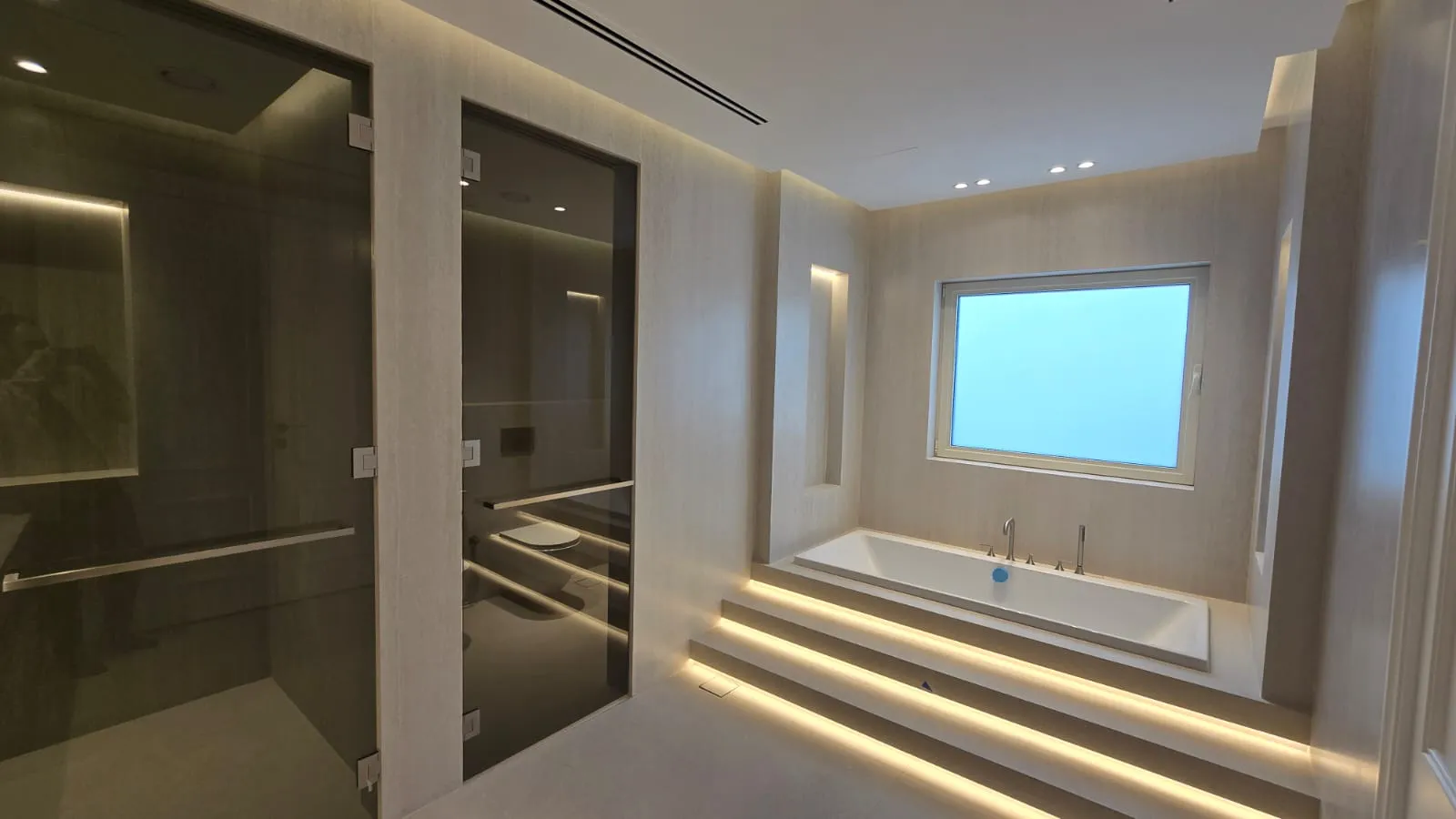 Meadows master bathroom after renovation with rectangular bath and smoked glass enclosures