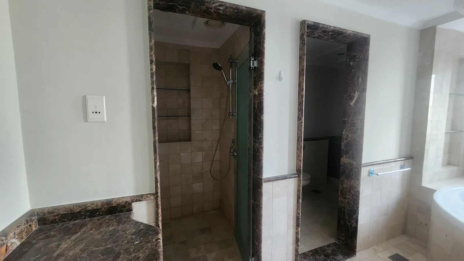 Master bathroom before renovation showing dark stone framed shower and WC entrances