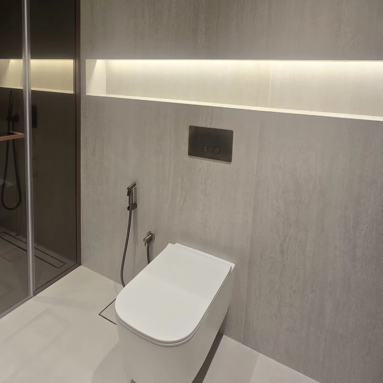 Wall-hung WC with concealed cistern, handheld bidet spray and illuminated recessed shelf in renovated Palm Jumeirah bathroom