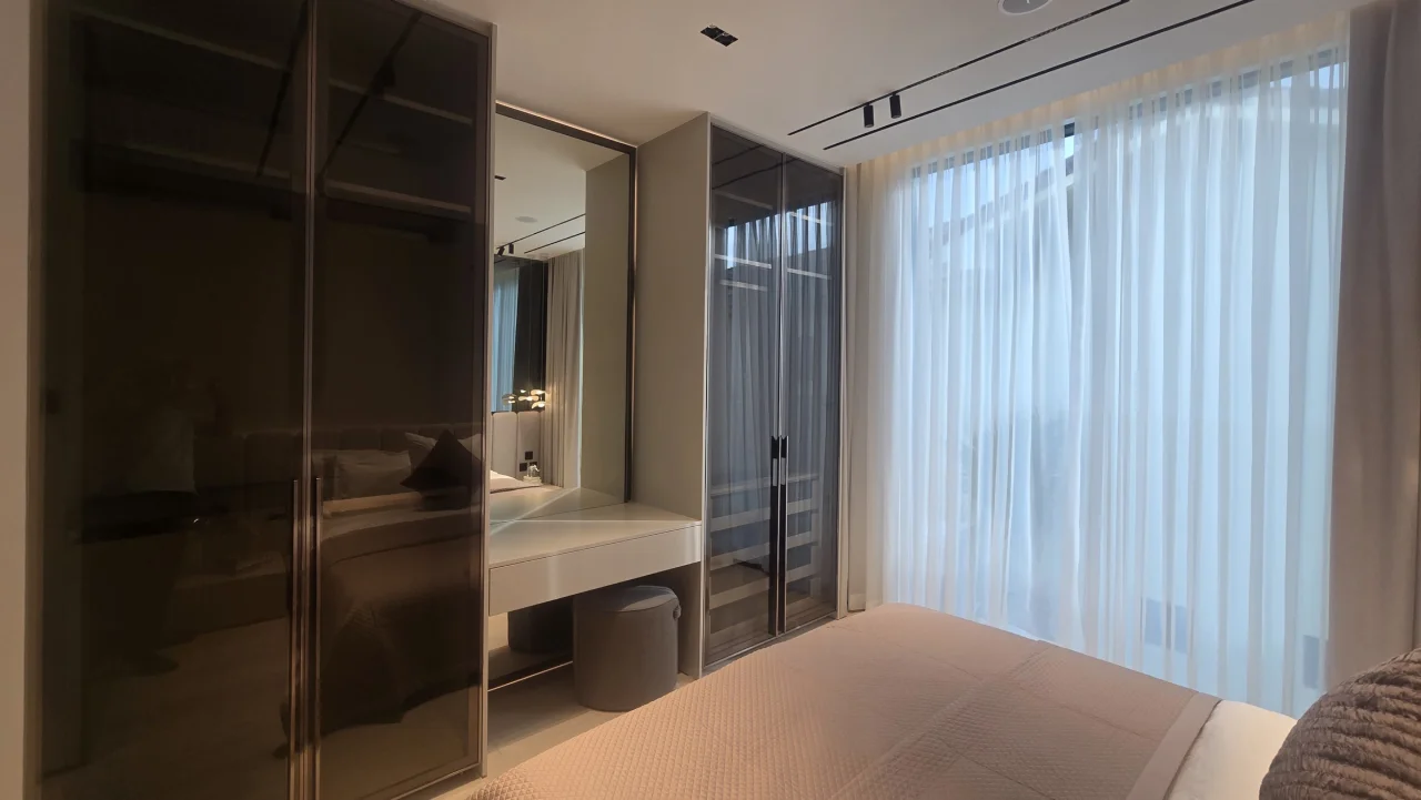 Palm Jumeirah guest bedroom after renovation with dark glass wardrobes, dressing table and full-height curtains
