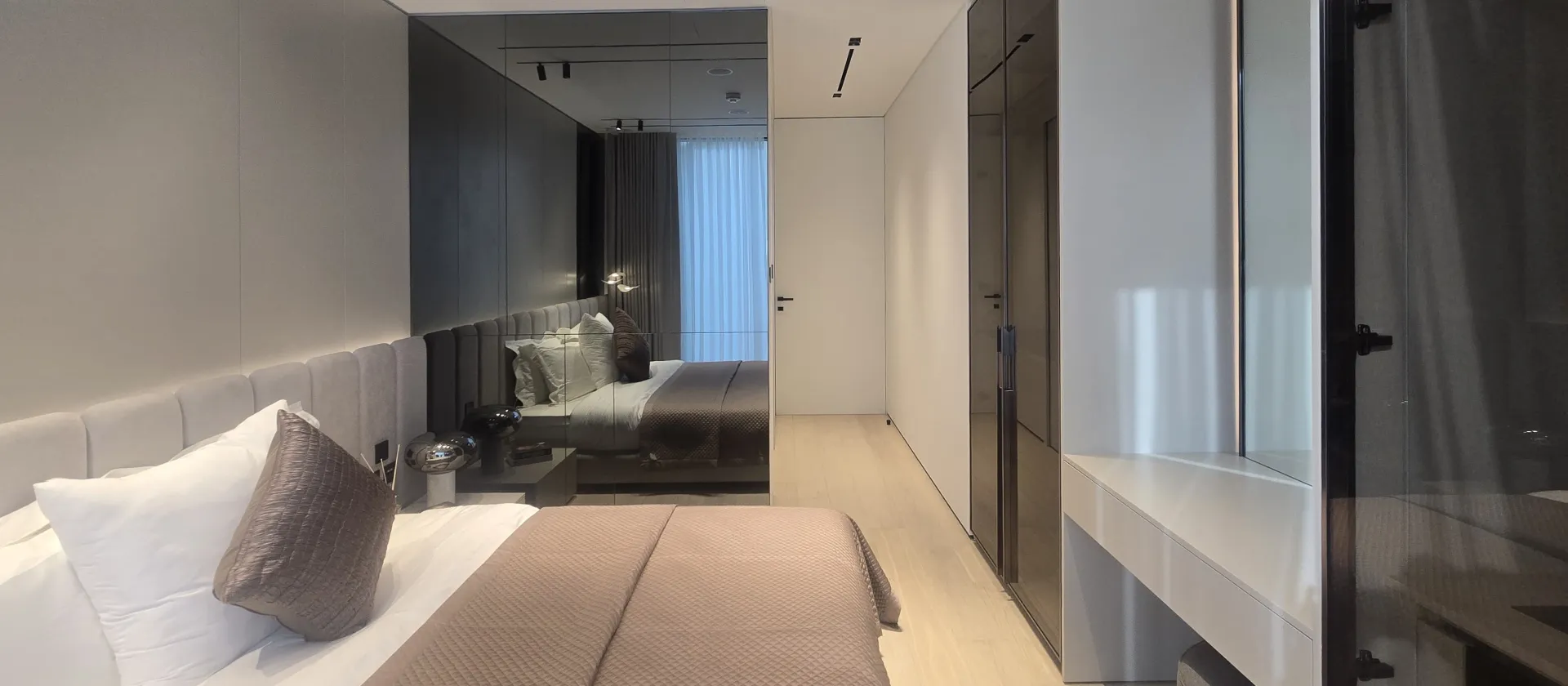 Renovated guest bedroom in Palm Jumeirah villa with upholstered headboard, mirrored wall and built-in wardrobes