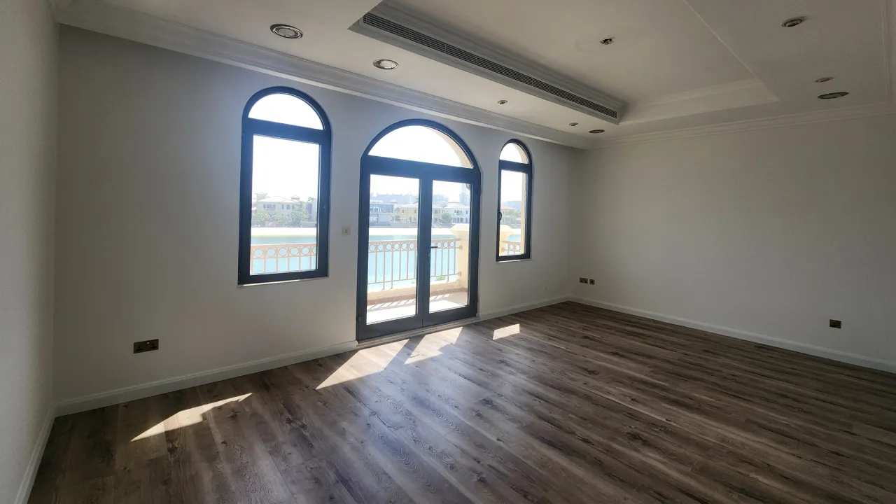 Palm Jumeirah bedroom before renovation with arched balcony doors, narrow windows and dark timber flooring