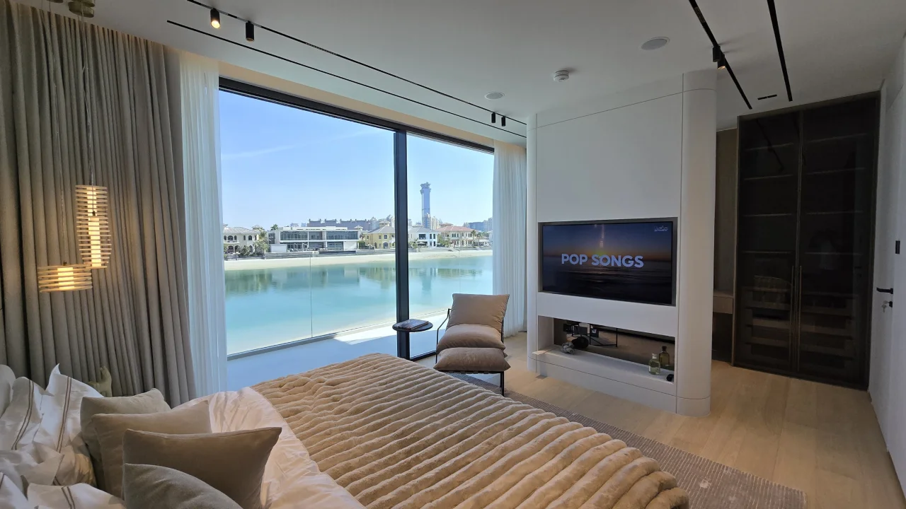 Renovated Palm Jumeirah bedroom with wide waterfront glazing, integrated TV wall and dressing area